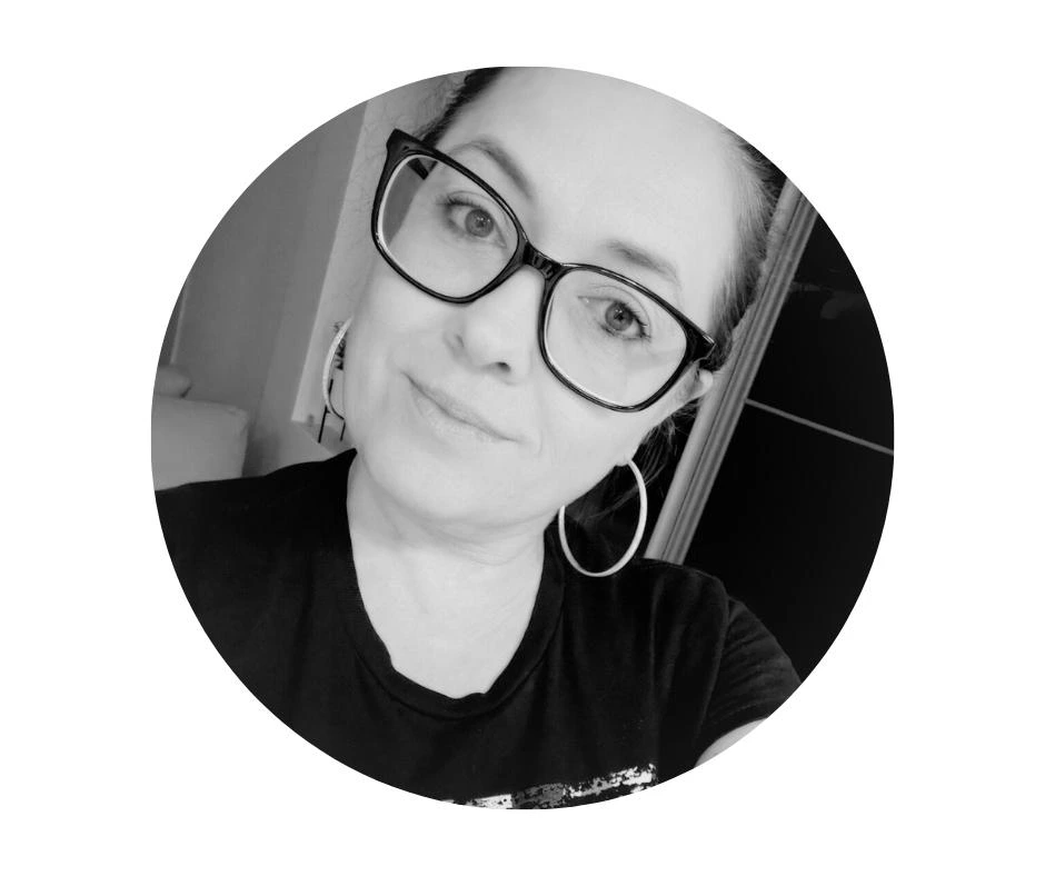 Meet our Babysitters Cherished Cherubs photo of a babysitter with glasses and hoop earrings, wearing a dark shirt, looking at the camera with a neutral expression.