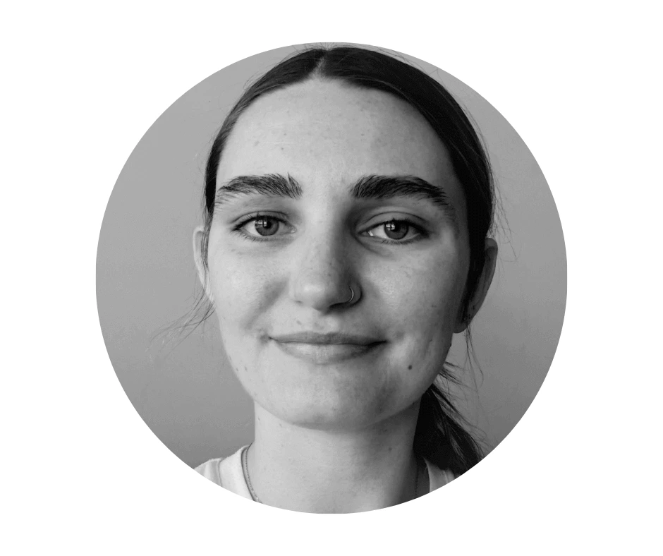 Meet our Babysitters Black and white portrait of a Cherished Cherubs Babysitter with long dark hair, a nose ring, and a slight smile, looking directly at the camera within a circular frame—an image reminiscent of Cherished Cherubs.