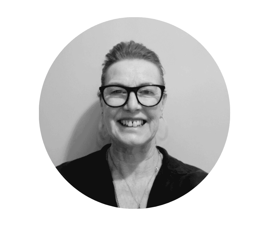 Meet our Babysitters Black and white portrait of a Cherished Cherubs Babysitter with glasses, smiling, wearing a dark top, in front of a plain background, beautifully captured by Cherished Cherubs inside a circular frame.