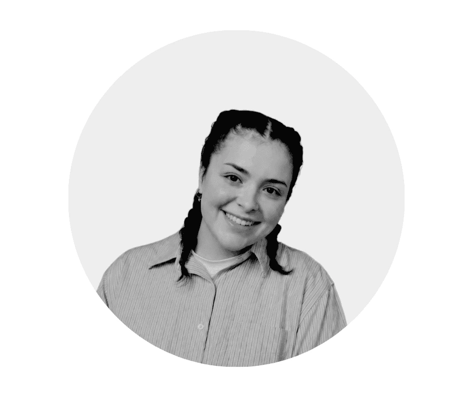 A Cherished Cherubs Babysitter with braided hair is smiling at the camera, wearing a striped button-up shirt and earrings, embodying the warmth of Cherished Cherubs, in front of a plain light background.